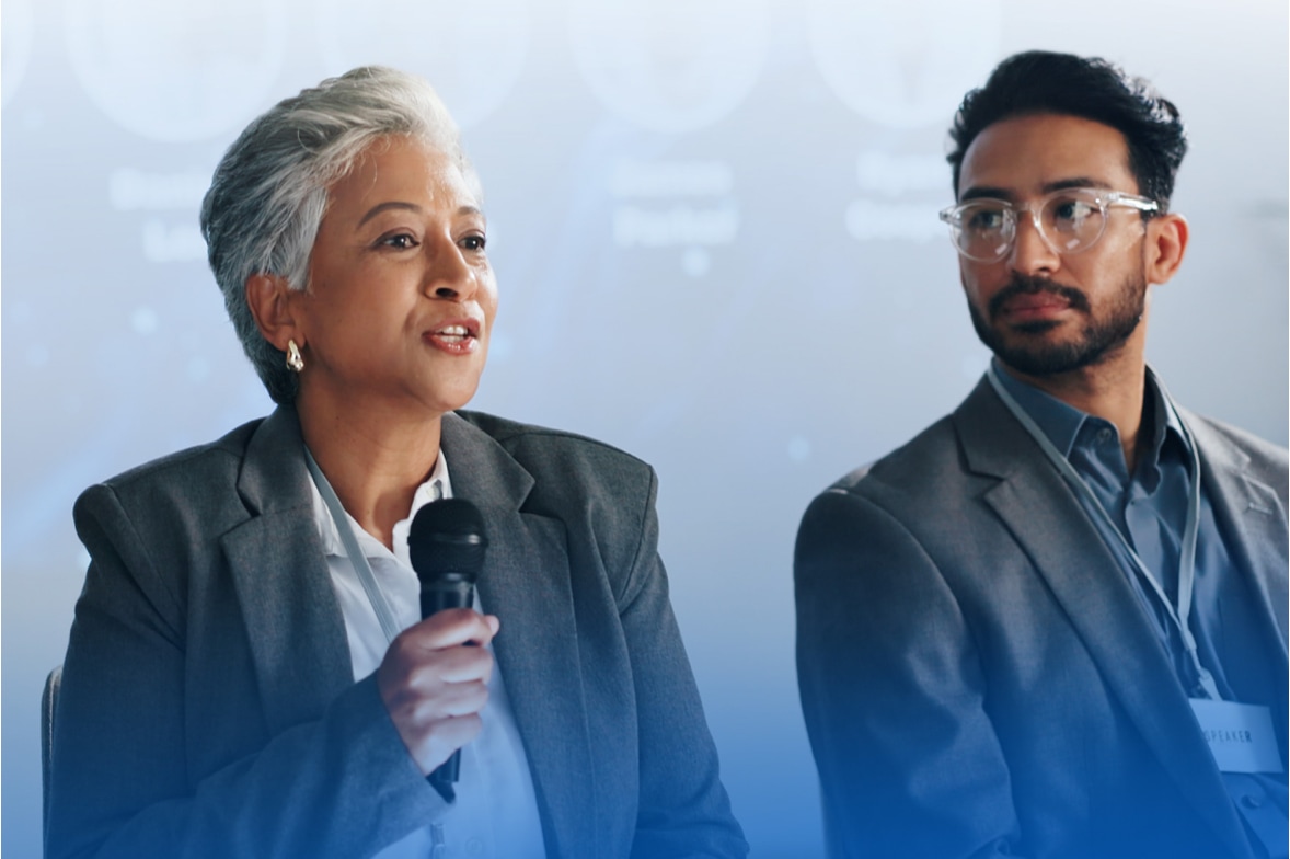 woman next to man speaks on conference stage