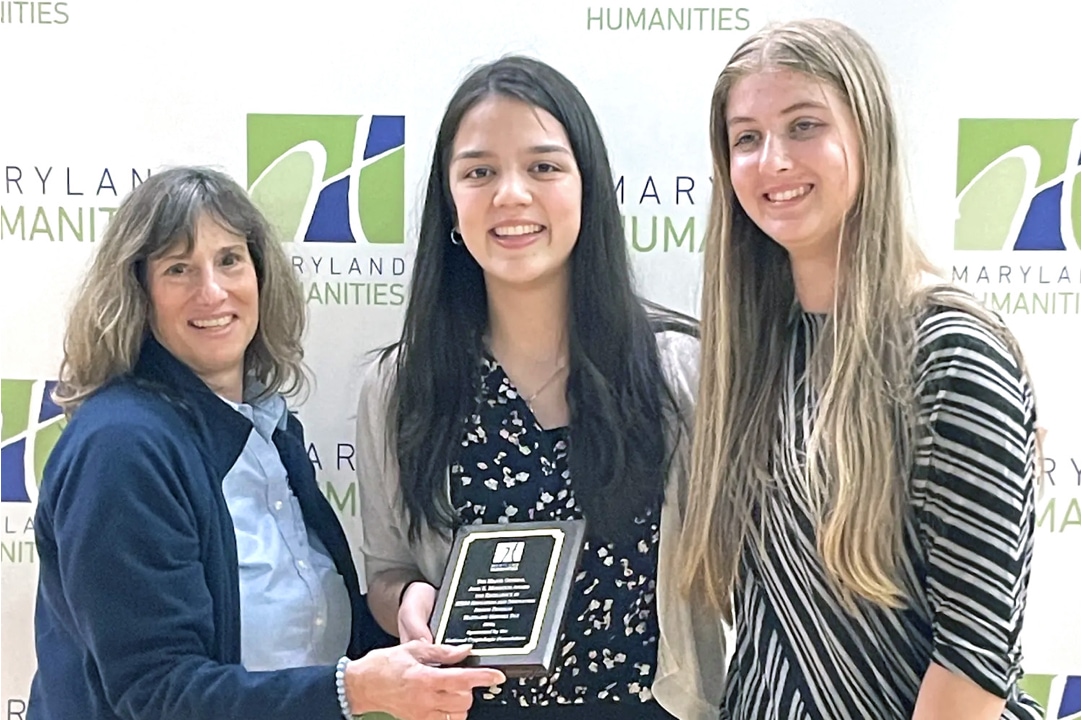 two students receiving award from woman