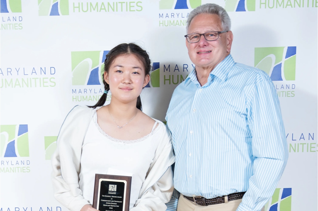 student next to man holds up award for cybersecurity achievement